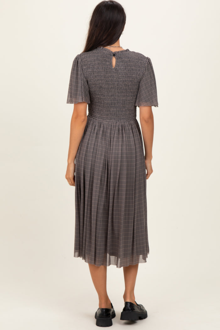 woman wearing a grey plaid midi dress with short sleeves and a smocked bodice, view from the back