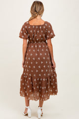 woman wearing a brown floral maternity dress with short sleeves and a tiered hem, showing the back view