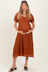 woman wearing an orange lace maternity dress and holding her baby bump