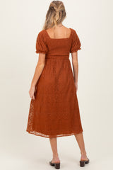 woman wearing a rust-colored maternity dress with puff sleeves and a smocked bodice, showing a relaxed fit in the back