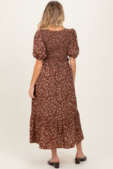 woman wearing a brown floral maternity dress with puff sleeves and a tiered skirt, showing a baby bump from the back