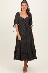 woman wearing a black floral print maxi dress with puff sleeves and a tiered skirt
