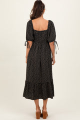 woman wearing a black midi dress with puff sleeves and a ruffled hem, seen from the back