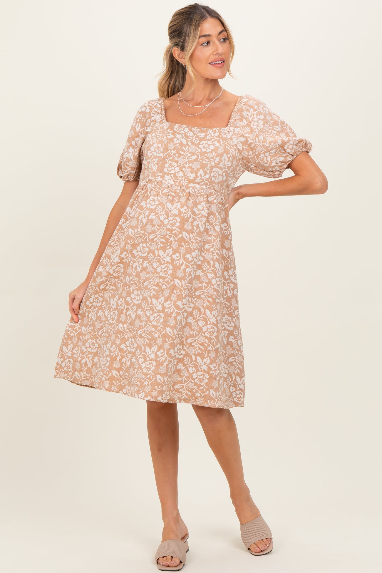 woman wearing a beige floral maternity dress with short puff sleeves and a square neckline
