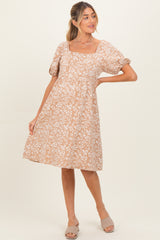 woman wearing a beige floral maternity dress with short puff sleeves and a square neckline