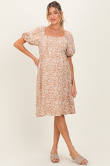 woman wearing a beige floral maternity dress with puff sleeves and a square neckline, showcasing her baby bump