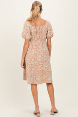 woman wearing a floral print beige maternity dress with a smocked back and puff sleeves