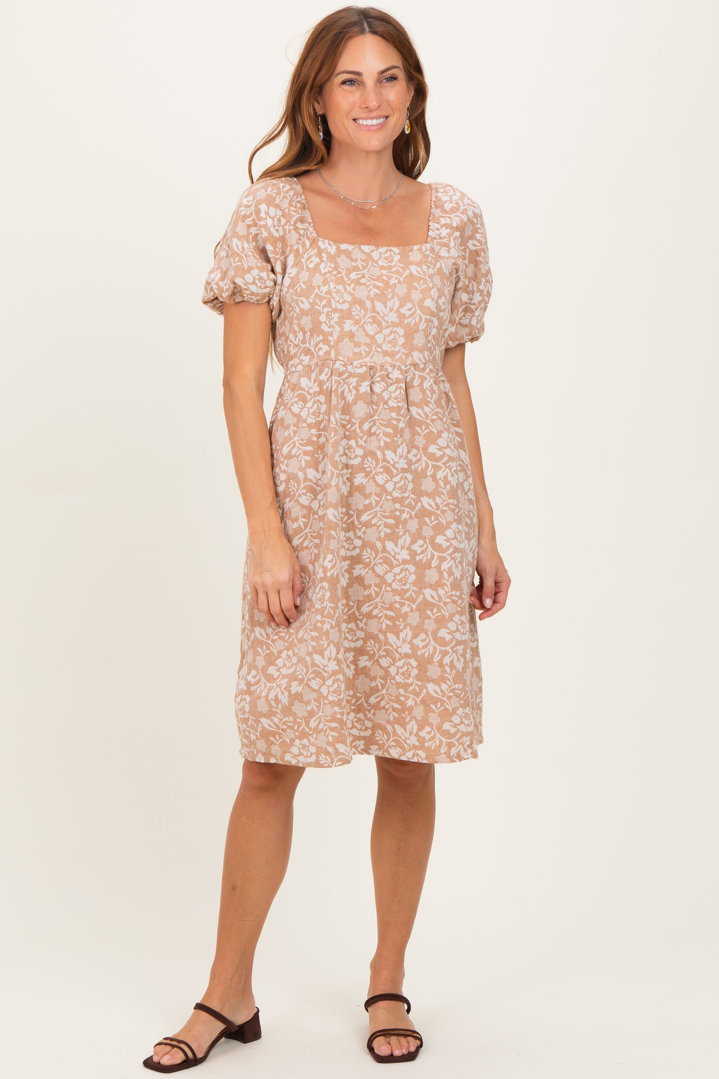 woman wearing a short beige floral print dress with puffed sleeves and a square neckline