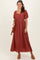 woman wearing a rust colored maxi dress with puff sleeves and lace detailing, holding a brown crossbody bag