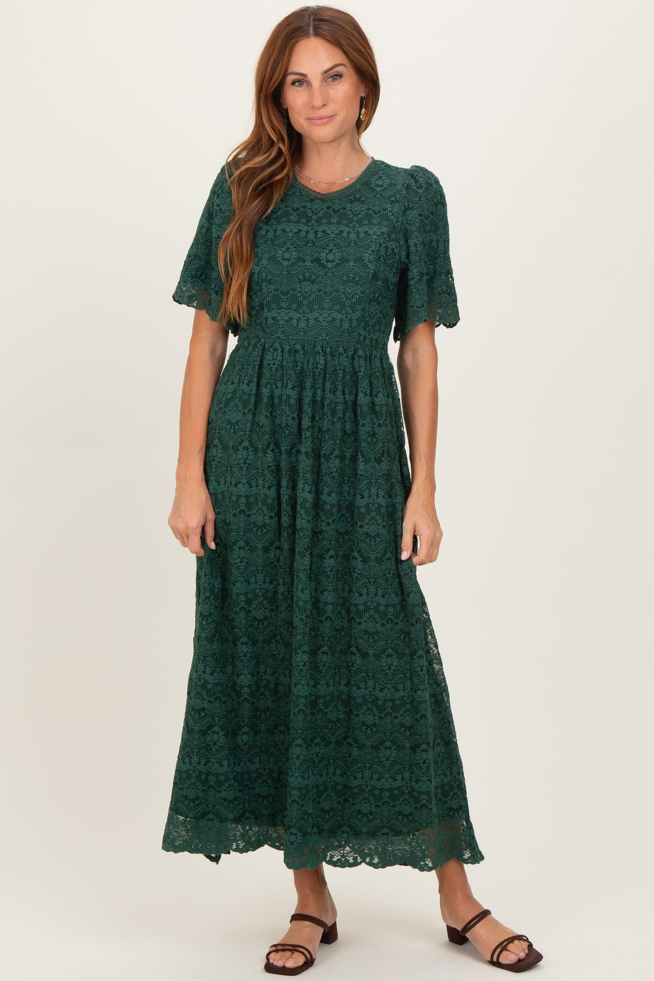 woman wearing a dark green lace maxi dress with short sleeves and a flared skirt