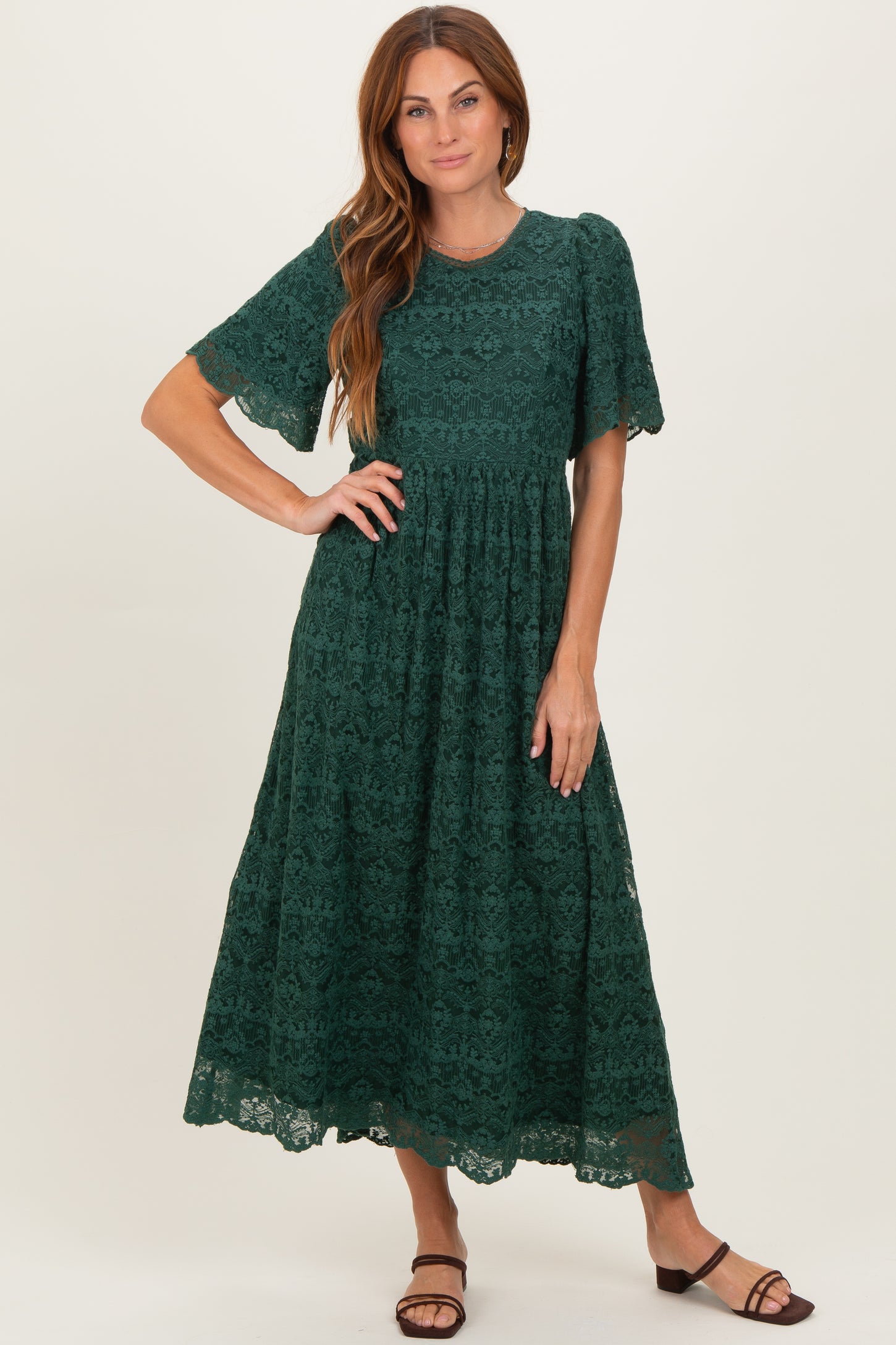 woman wearing a green lace maxi dress with short sleeves and a fitted bodice