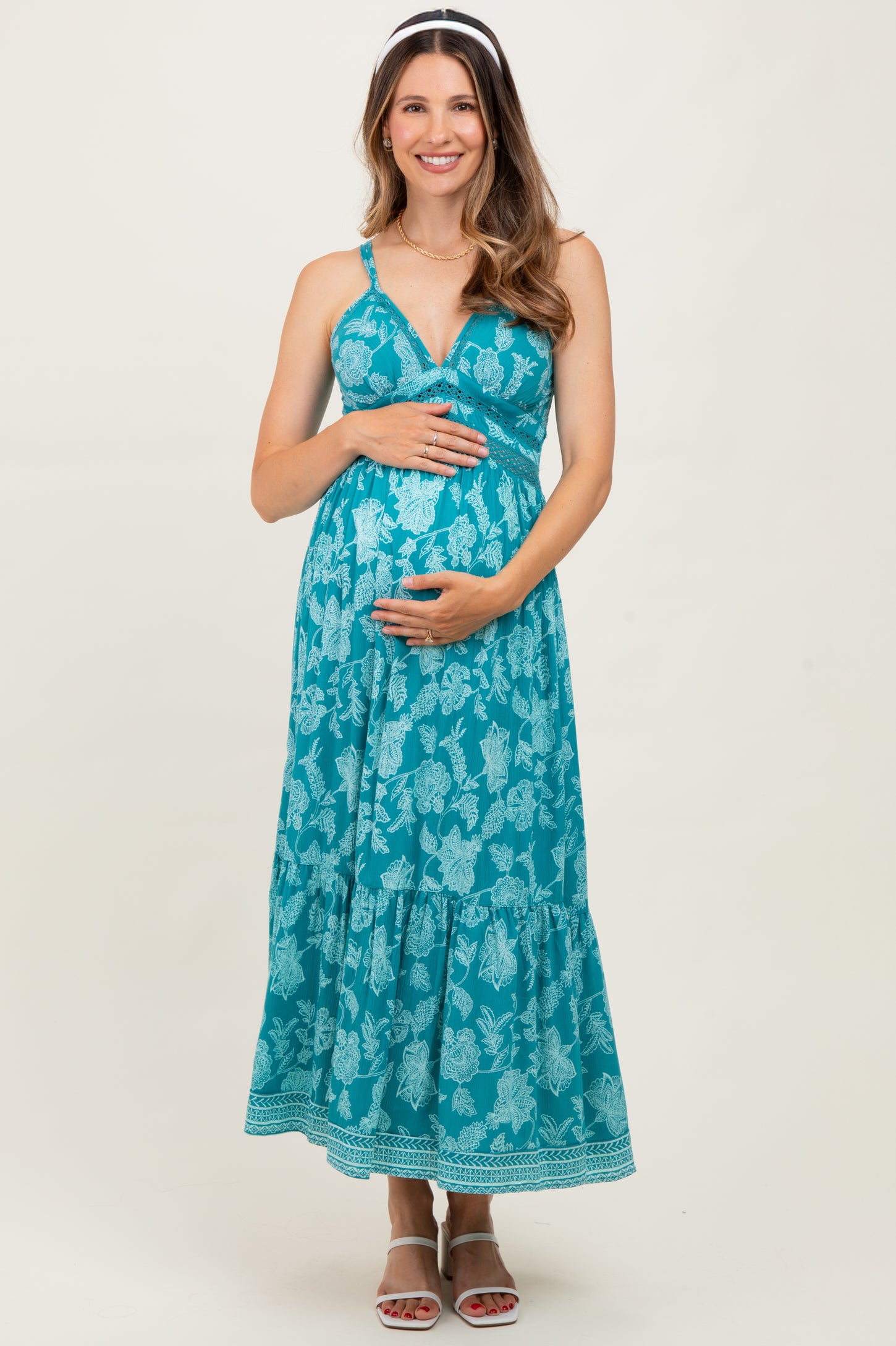 woman wearing a turquoise floral maternity maxi dress and holding her baby bump