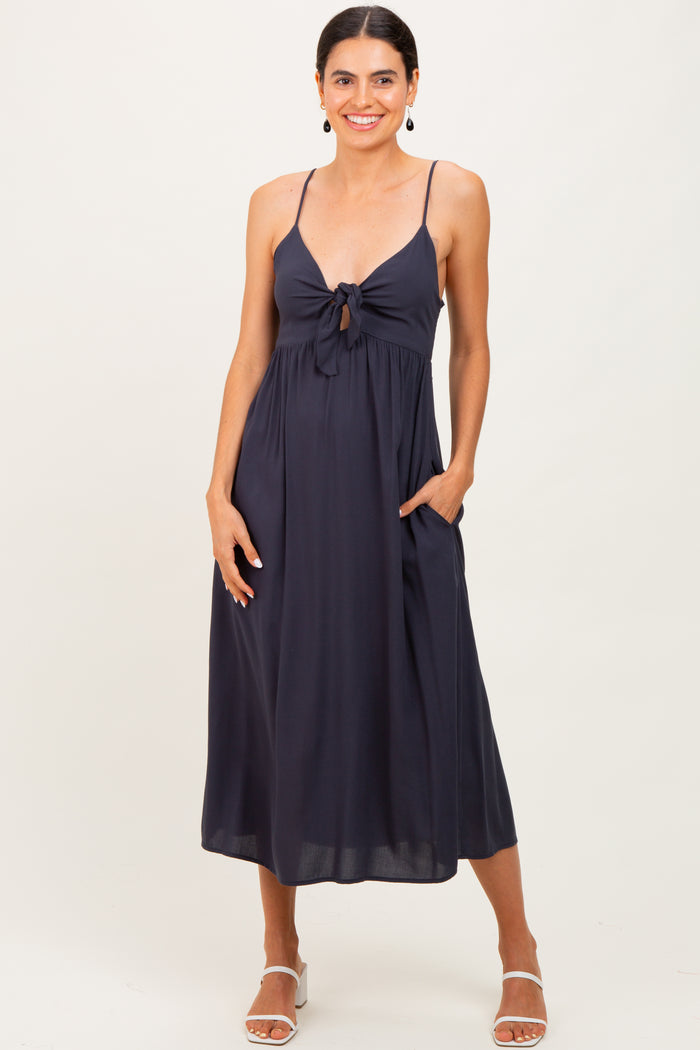 woman wearing a dark navy midi dress with a front knot detail and side pockets