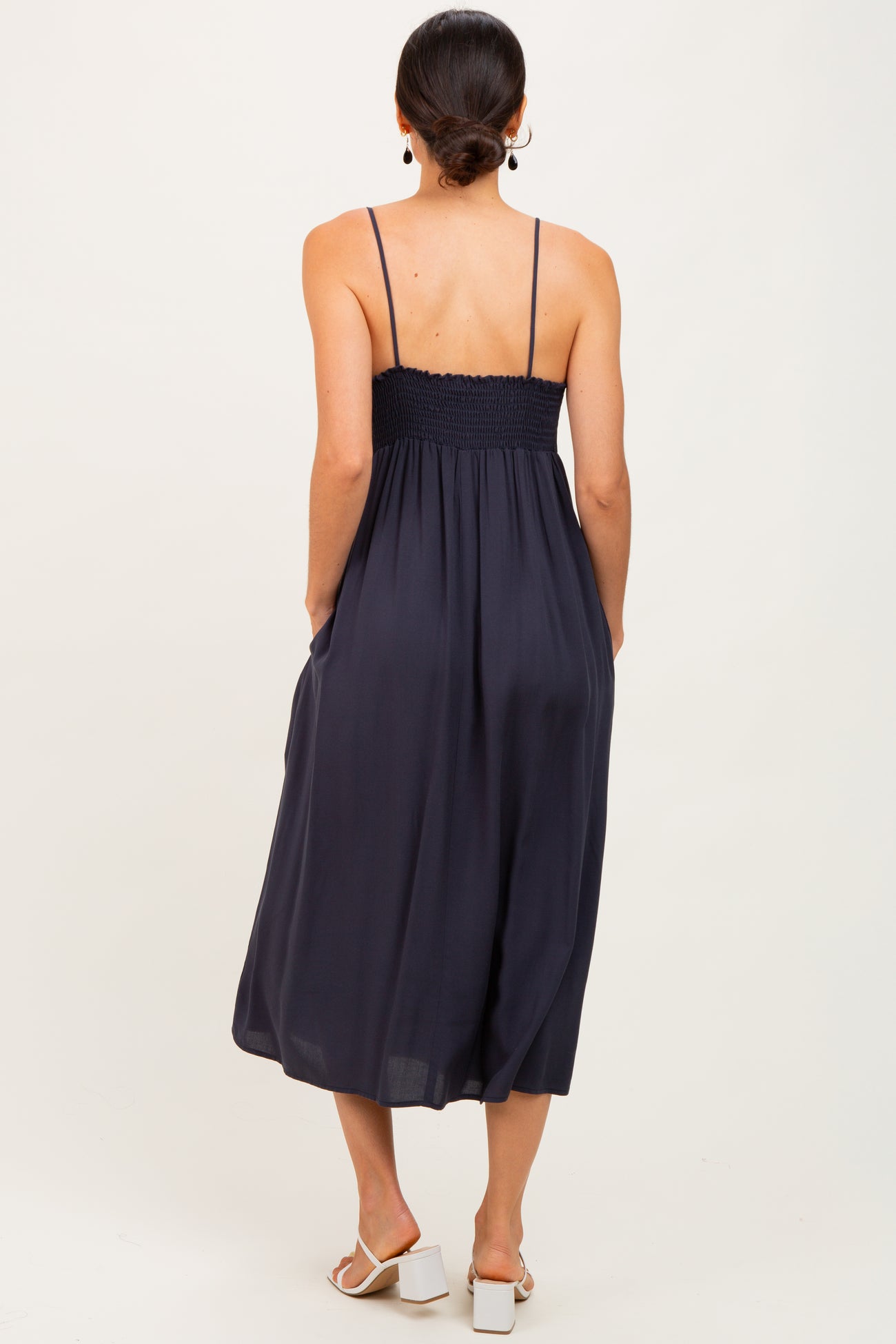 woman wearing a navy blue sleeveless maxi dress with a smocked bodice and pockets