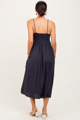 woman wearing a navy blue sleeveless maxi dress with a smocked bodice and pockets