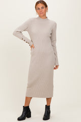 woman wearing a light beige ribbed midi dress with long sleeves and button detail, paired with black ankle boots
