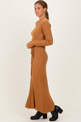 woman wearing a brown ribbed long sleeve maxi dress with a tie waist and flared hem, styled with black heeled boots