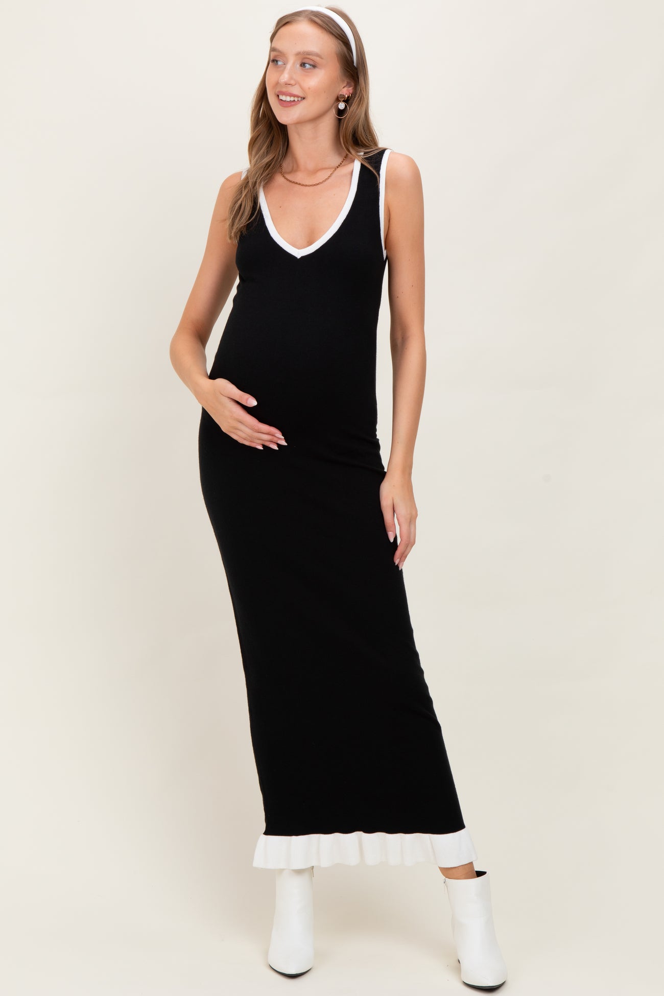 woman wearing a black maternity maxi dress with a white neckline and hem, showcasing her baby bump
