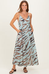 woman wearing a light blue maxi dress with a brown and gray abstract pattern and pockets, posing with a smile
