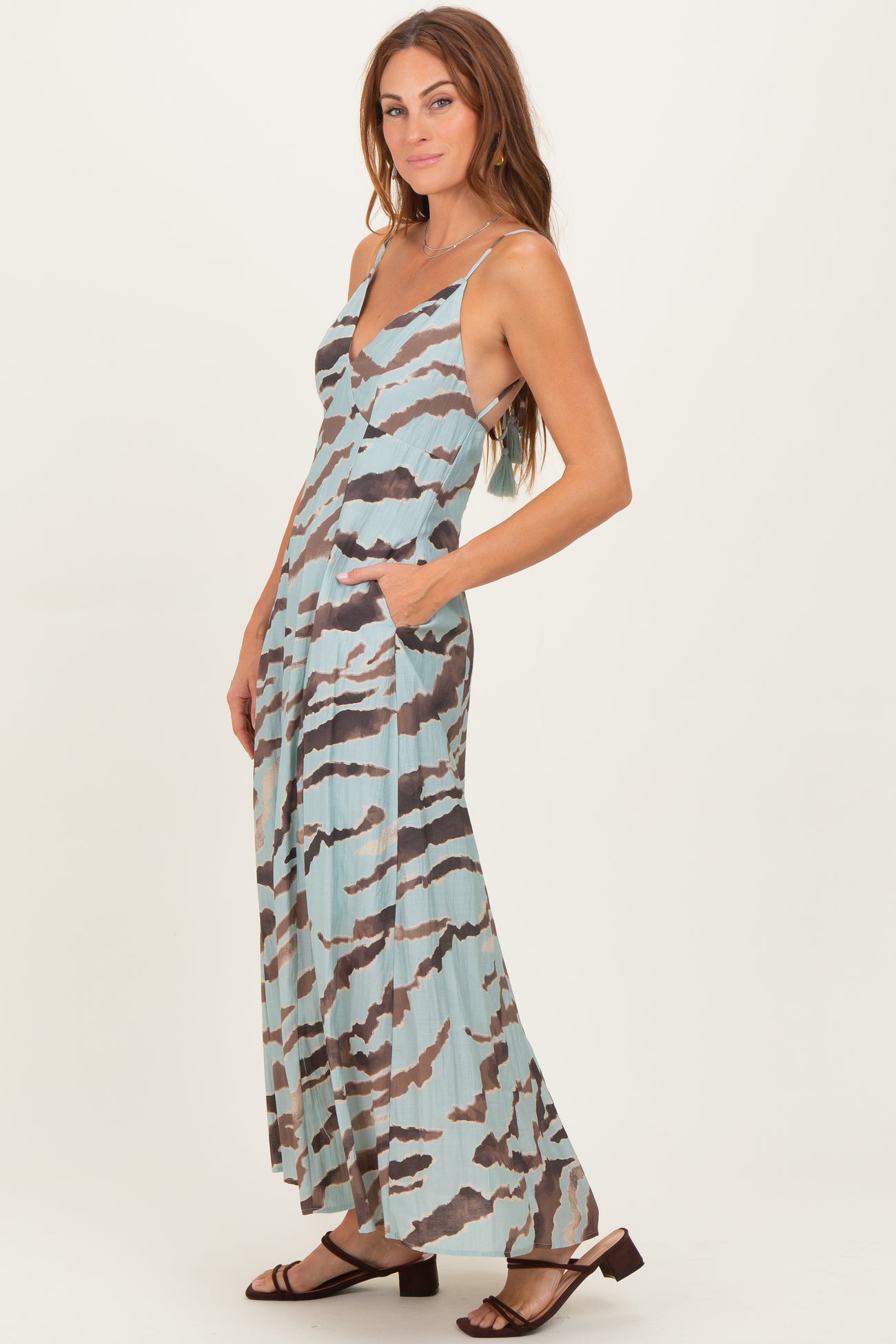 woman wearing a light blue and brown striped maxi dress with pockets and adjustable straps