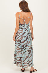 woman wearing a backless maxi dress with a light blue and brown abstract print, showing adjustable spaghetti straps