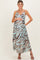 woman wearing a patterned maxi maternity dress in blue and brown, holding her baby bump with a smile
