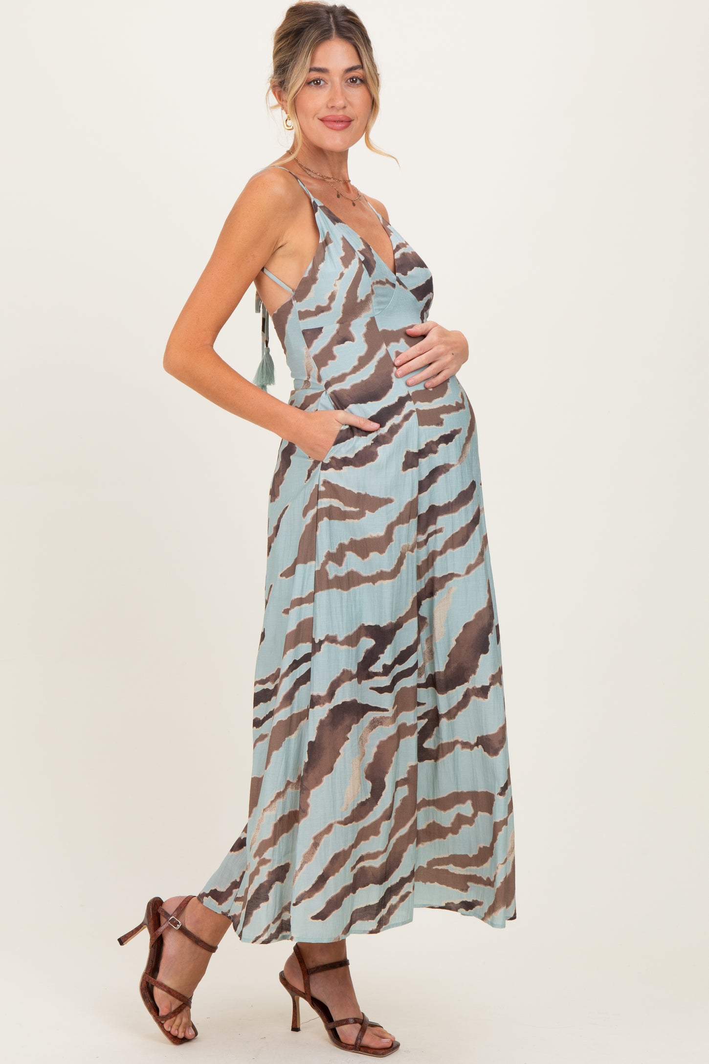 woman wearing a blue and brown striped maternity maxi dress with pockets and a visible baby bump