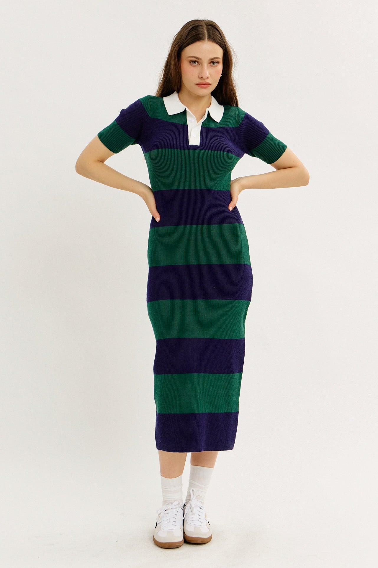 woman wearing a striped midi dress in green and navy with a white collar and short sleeves, paired with white sneakers