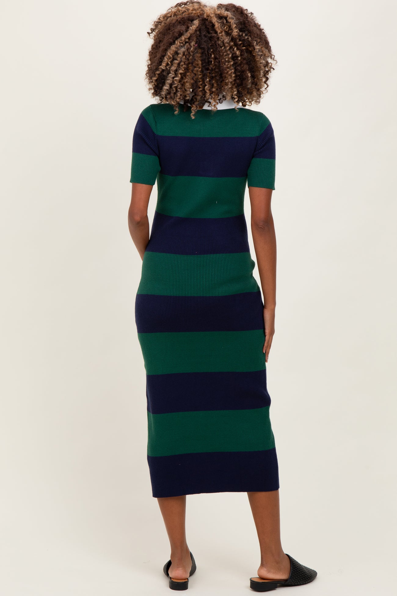 woman wearing a navy and green striped maternity dress with short sleeves and a fitted silhouette, showing no baby bump