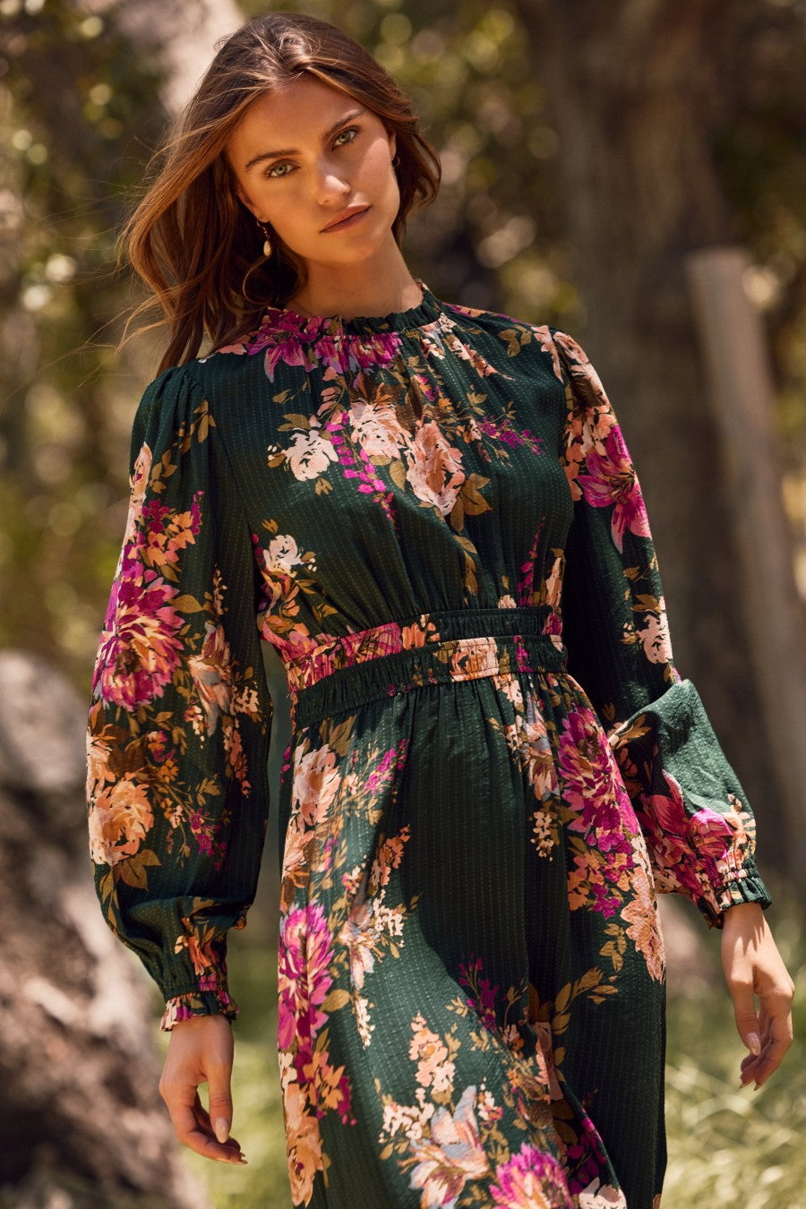 woman wearing a dark green floral maxi dress with puff sleeves and a cinched waist