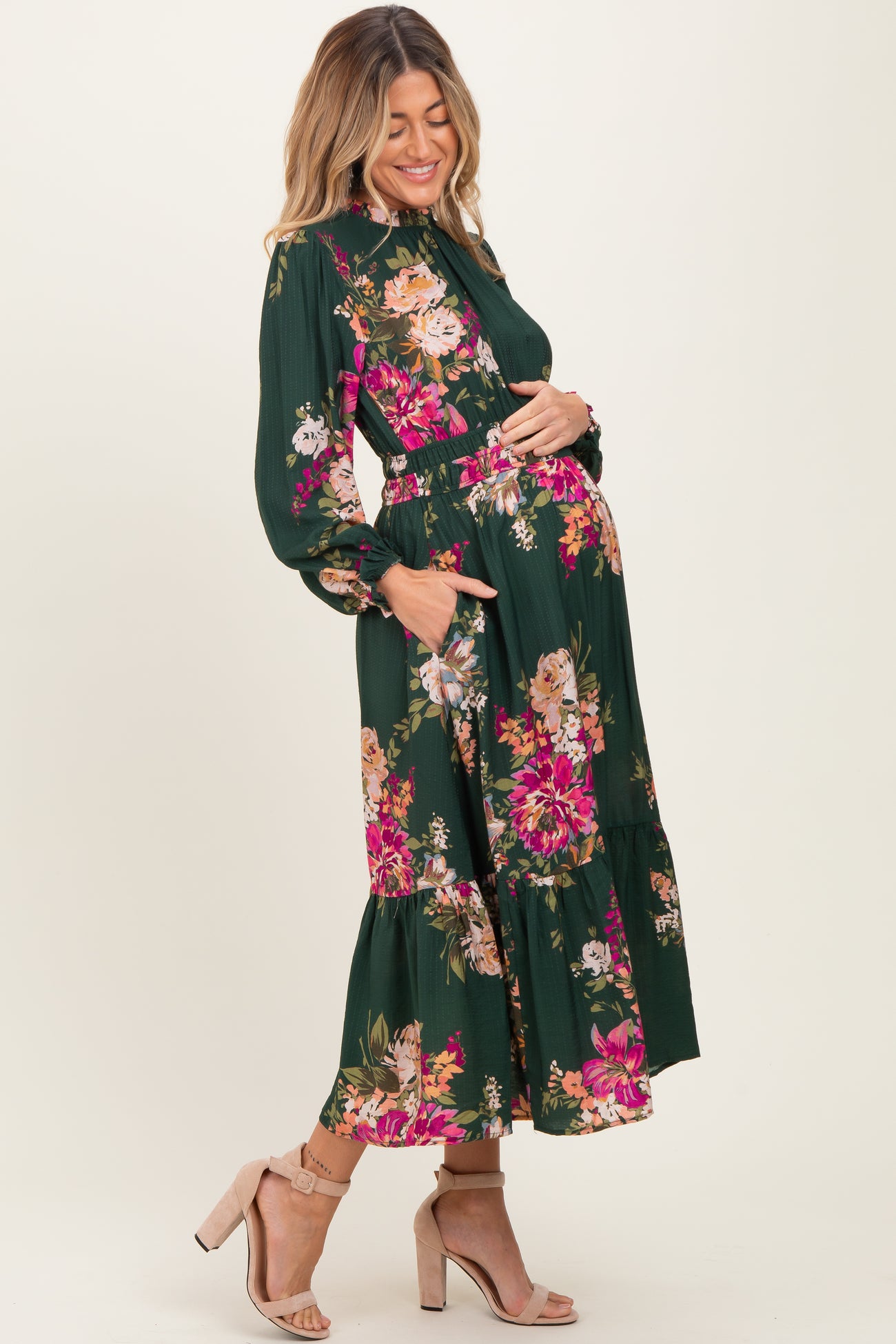 woman wearing a green floral print maternity maxi dress and holding her baby bump