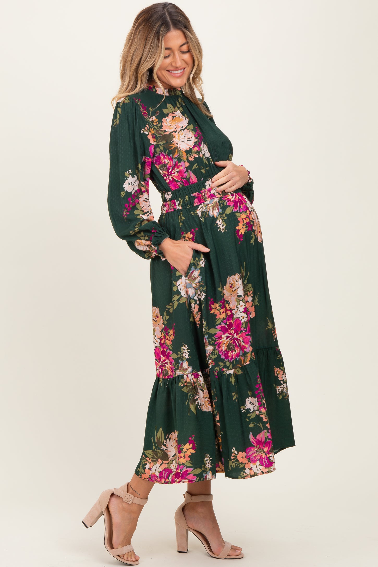 woman wearing a green floral print maternity maxi dress and holding her baby bump