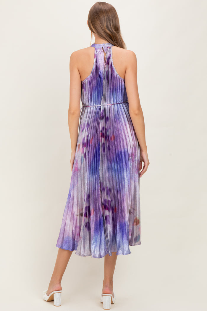 woman wearing a purple and blue tie-dye maternity dress with pleats and a halter neck, showing her baby bump