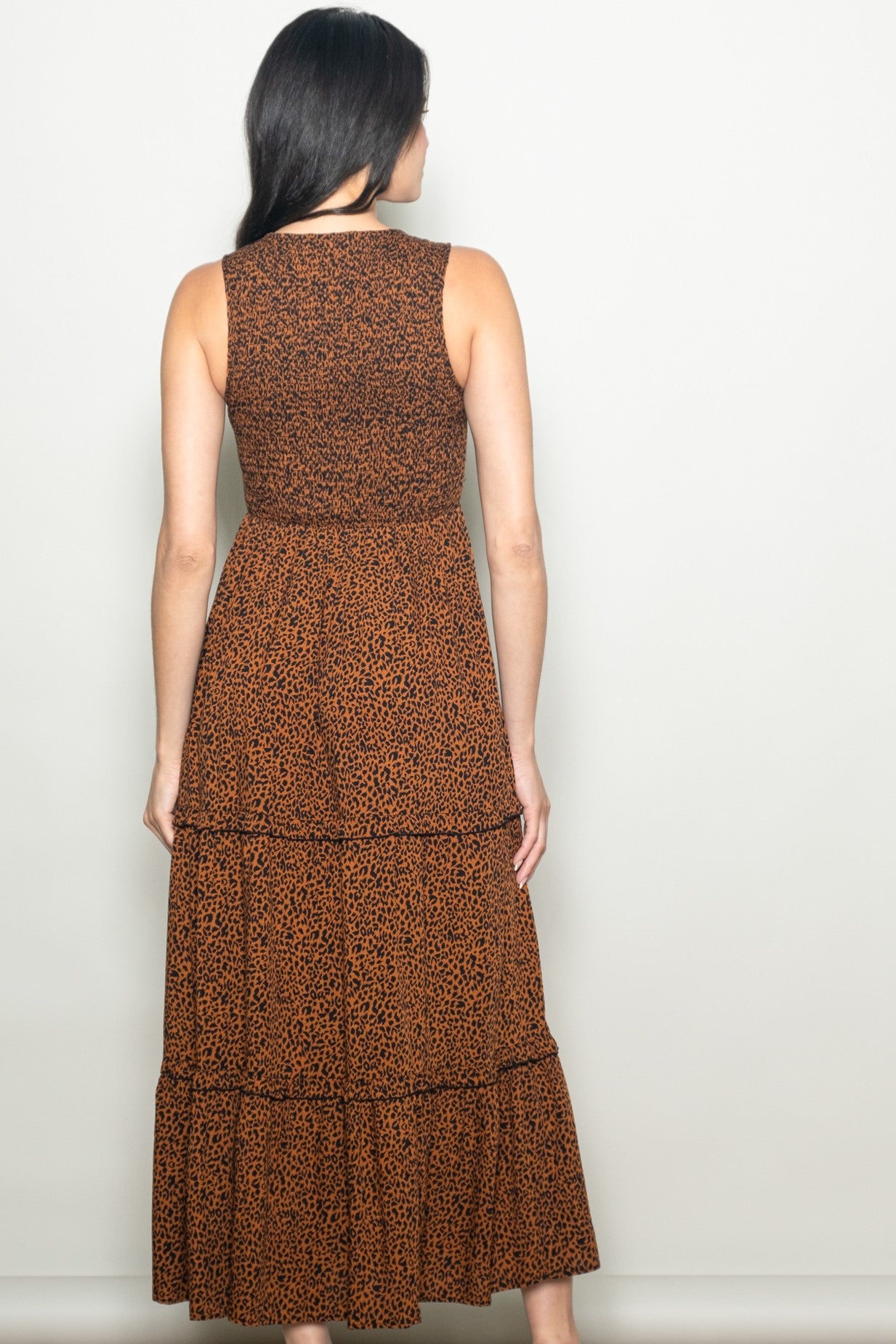 woman wearing a back view of a brown leopard print maxi dress with a tiered skirt