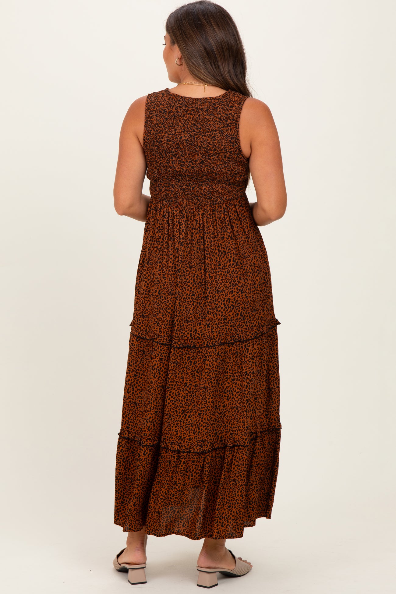 woman wearing a brown leopard print maternity maxi dress with tiered layers and a fitted bodice, showing her baby bump