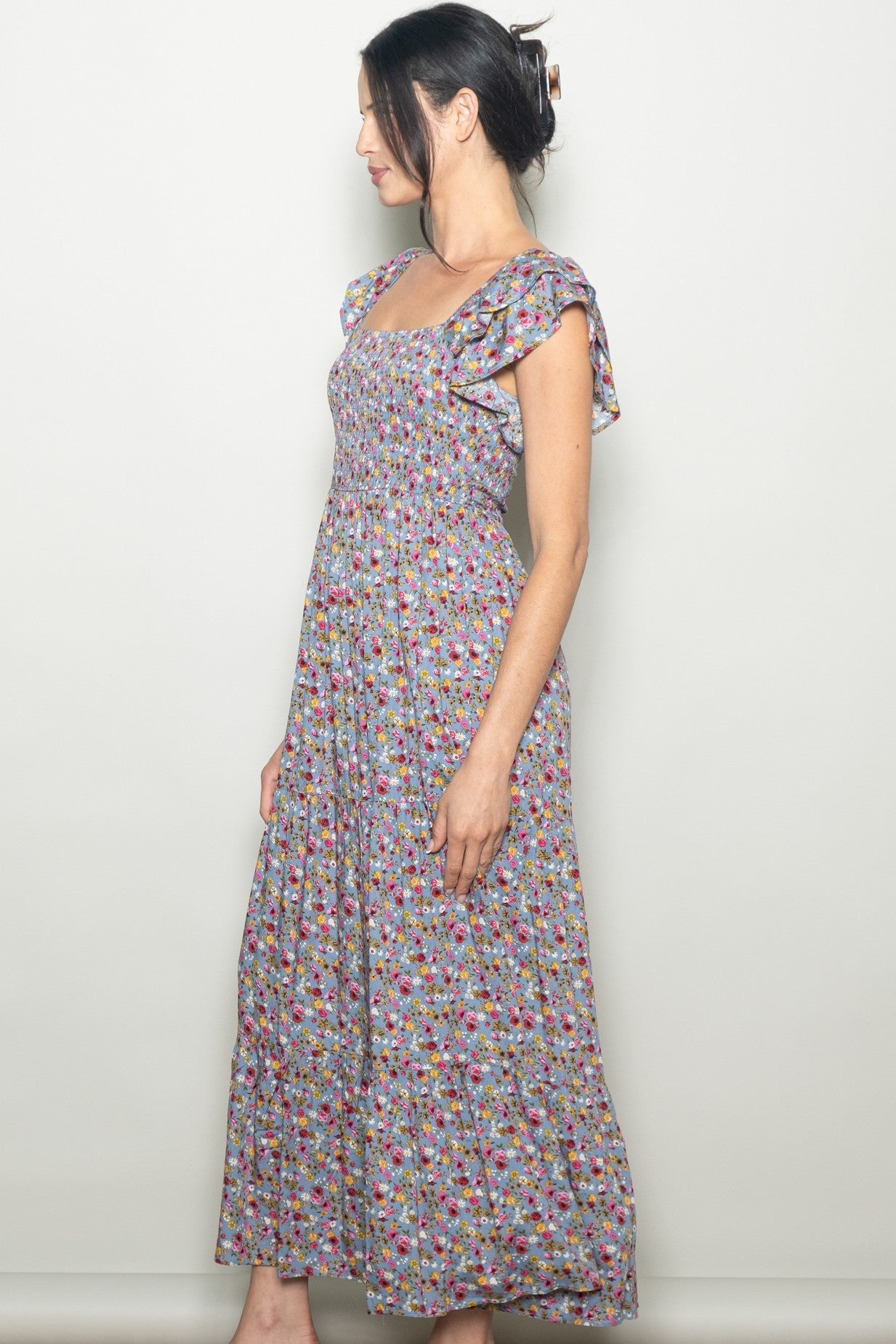 woman wearing a sleeveless floral maxi dress with ruffle sleeves and a fitted bodice