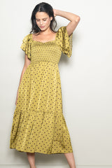 woman wearing a mustard polka dot midi dress with smocked bodice and flutter sleeves
