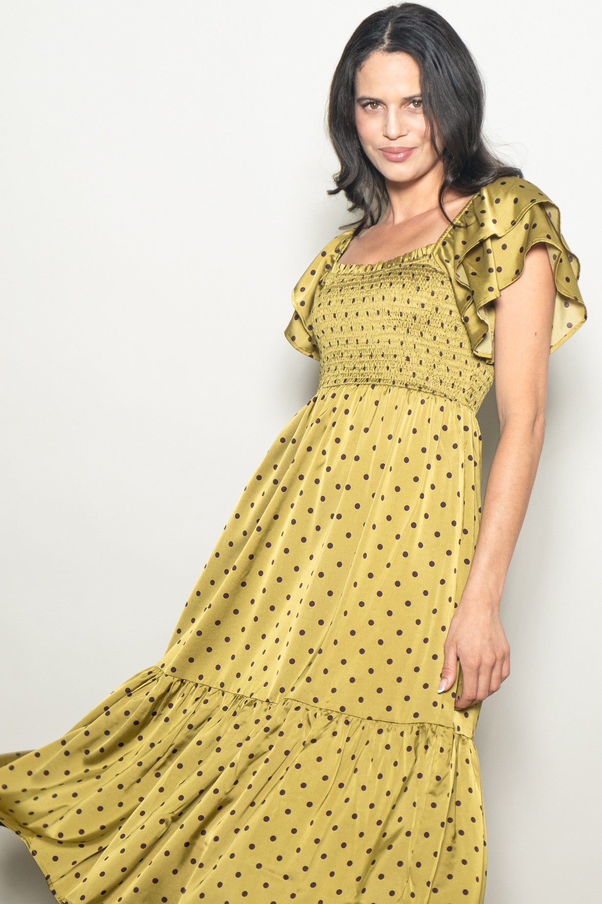 woman wearing a mustard yellow polka dot maxi dress with ruffled sleeves and a smocked bodice