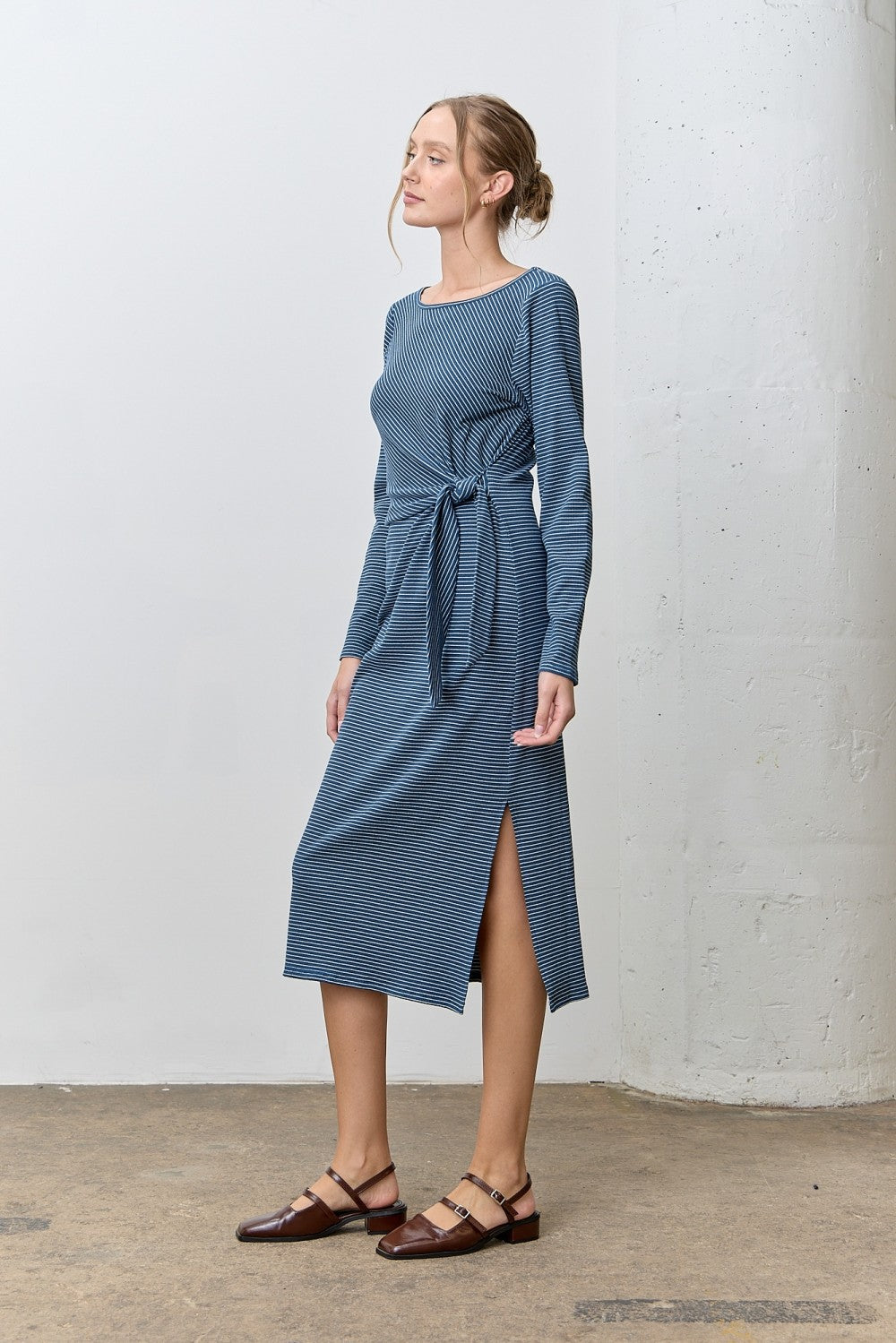 woman wearing a long sleeve blue striped midi dress with a tie waist and side slit