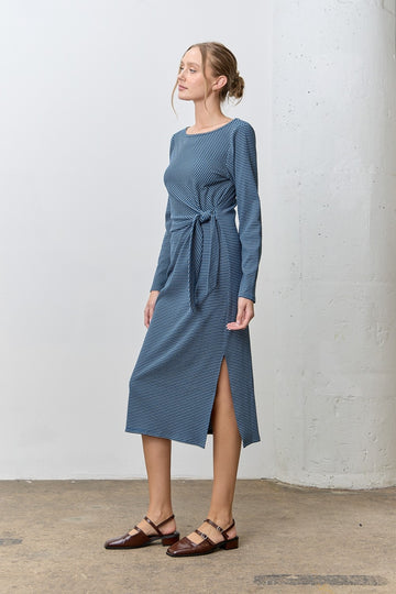 woman wearing a long sleeve blue striped midi dress with a tie waist and side slit