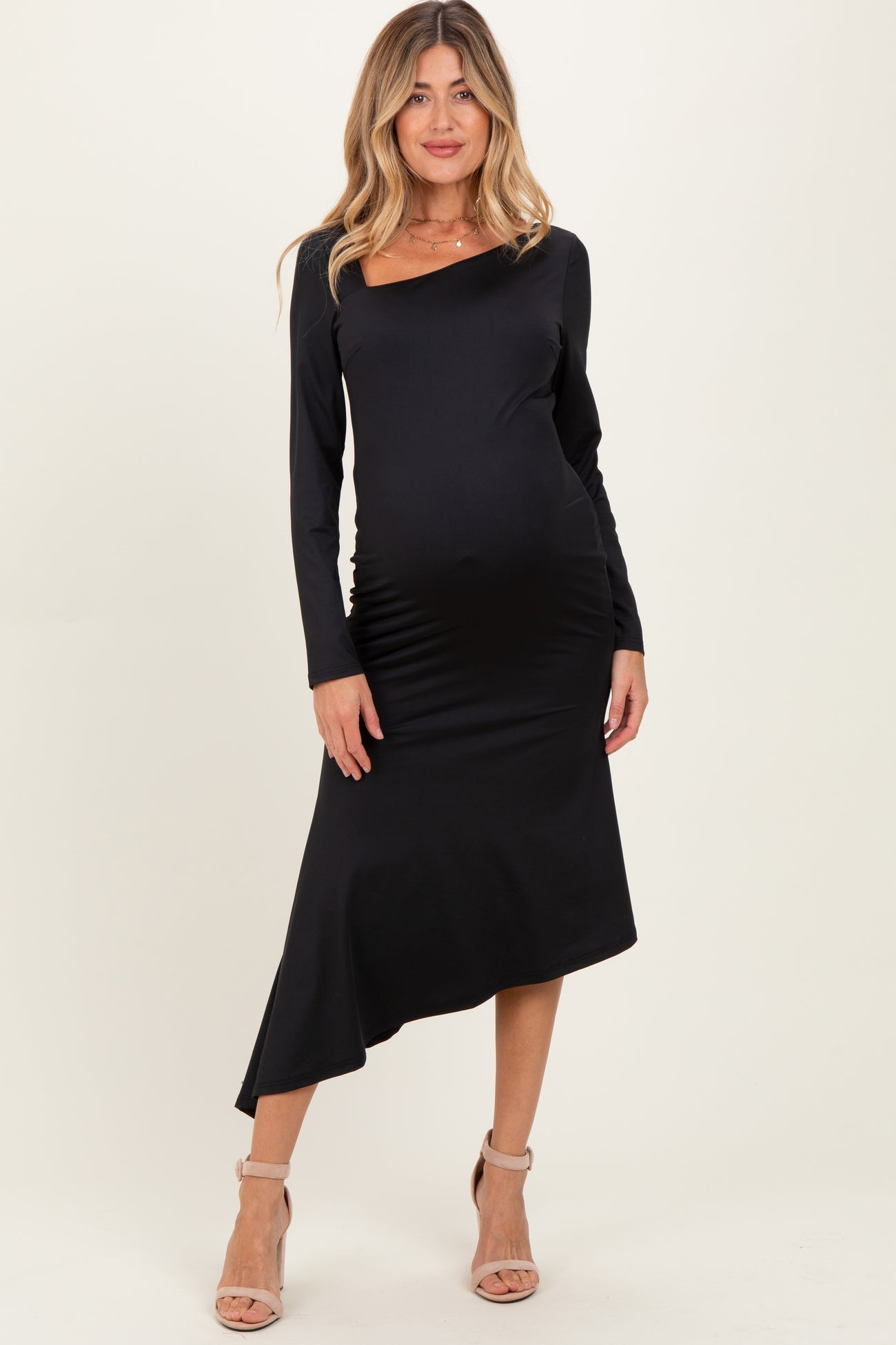 woman wearing a black long sleeve maternity dress with an asymmetrical hem and visible baby bump