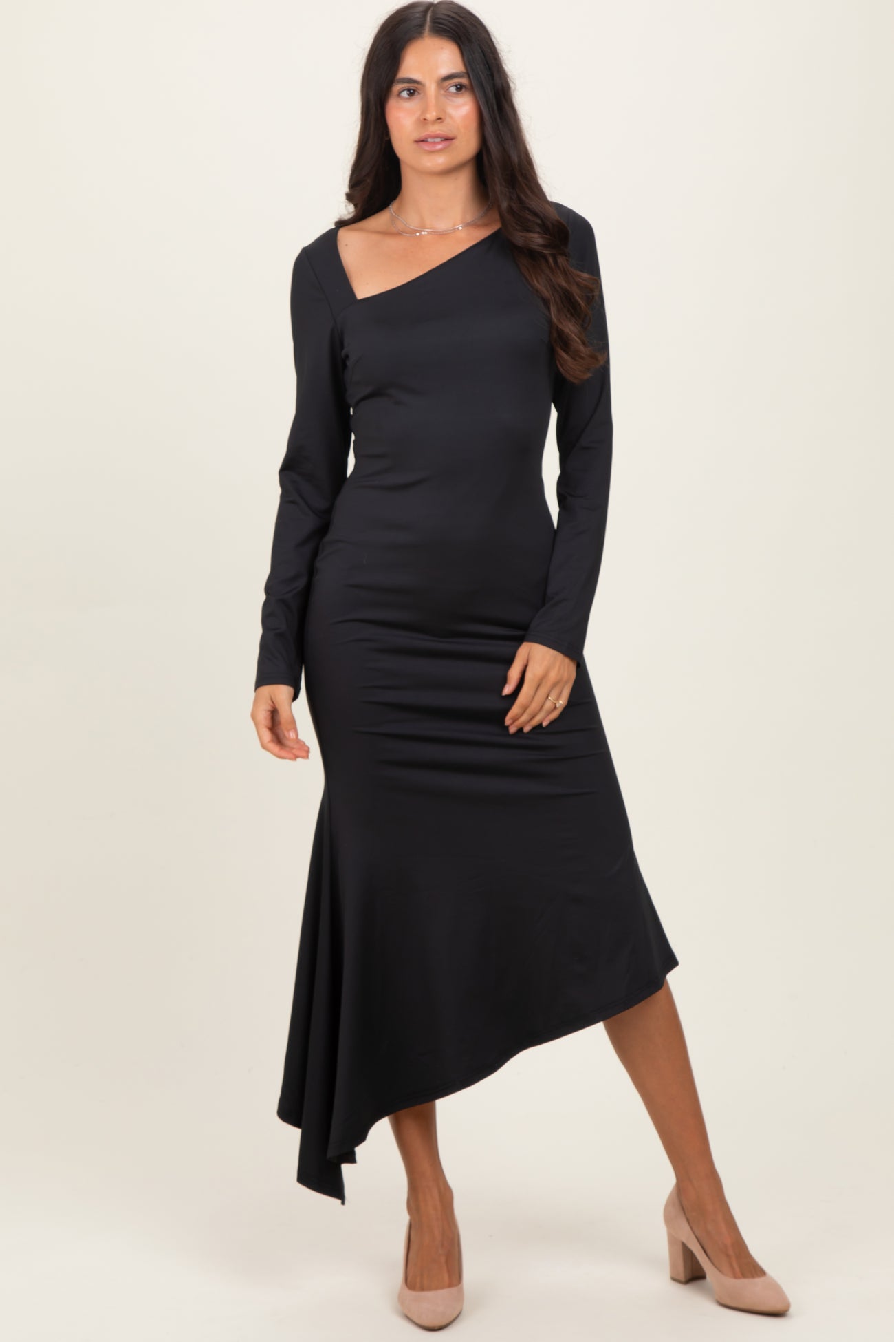 woman wearing a black one-shoulder long sleeve dress with an asymmetric hem and heels