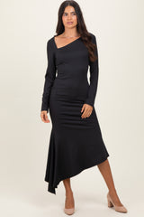 woman wearing a black one-shoulder long sleeve dress with an asymmetric hem and heels