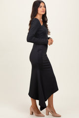 woman wearing a black long sleeve midi dress with an asymmetrical hem and nude heels