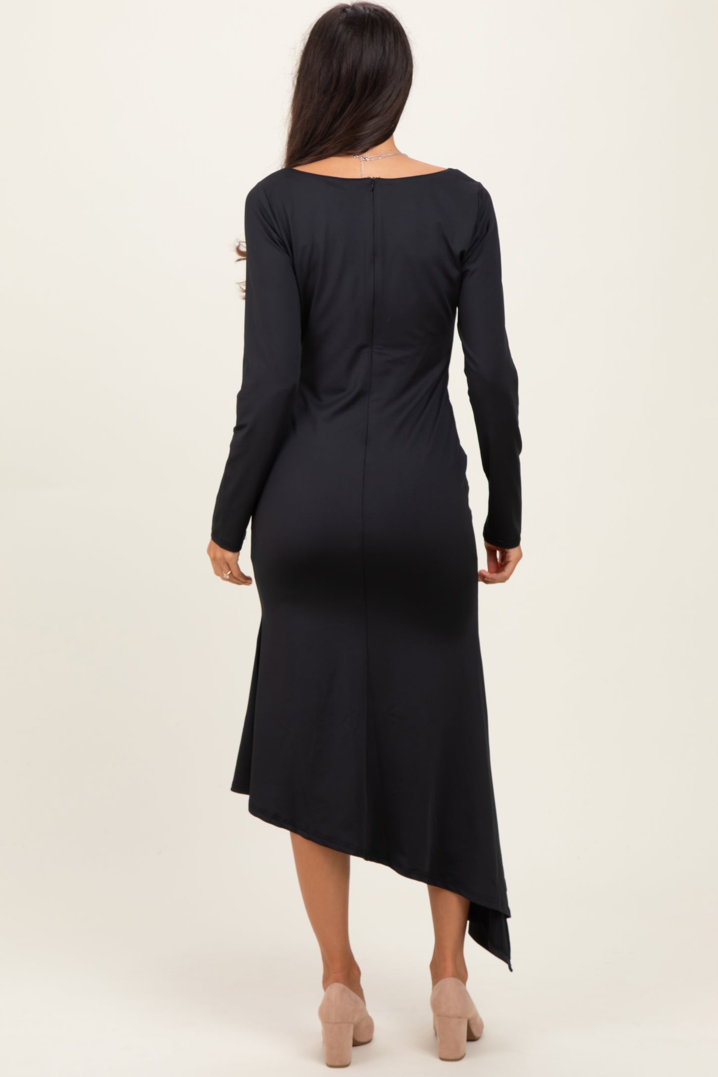 woman wearing a black long sleeve asymmetrical hem dress, viewed from the back