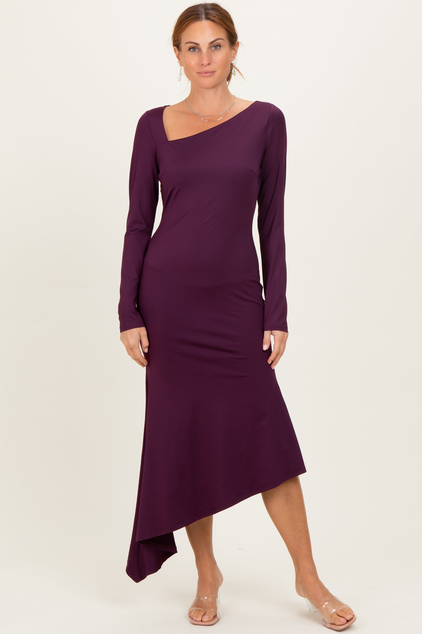 woman wearing a purple long sleeve asymmetrical dress with a sweetheart neckline and a fitted silhouette