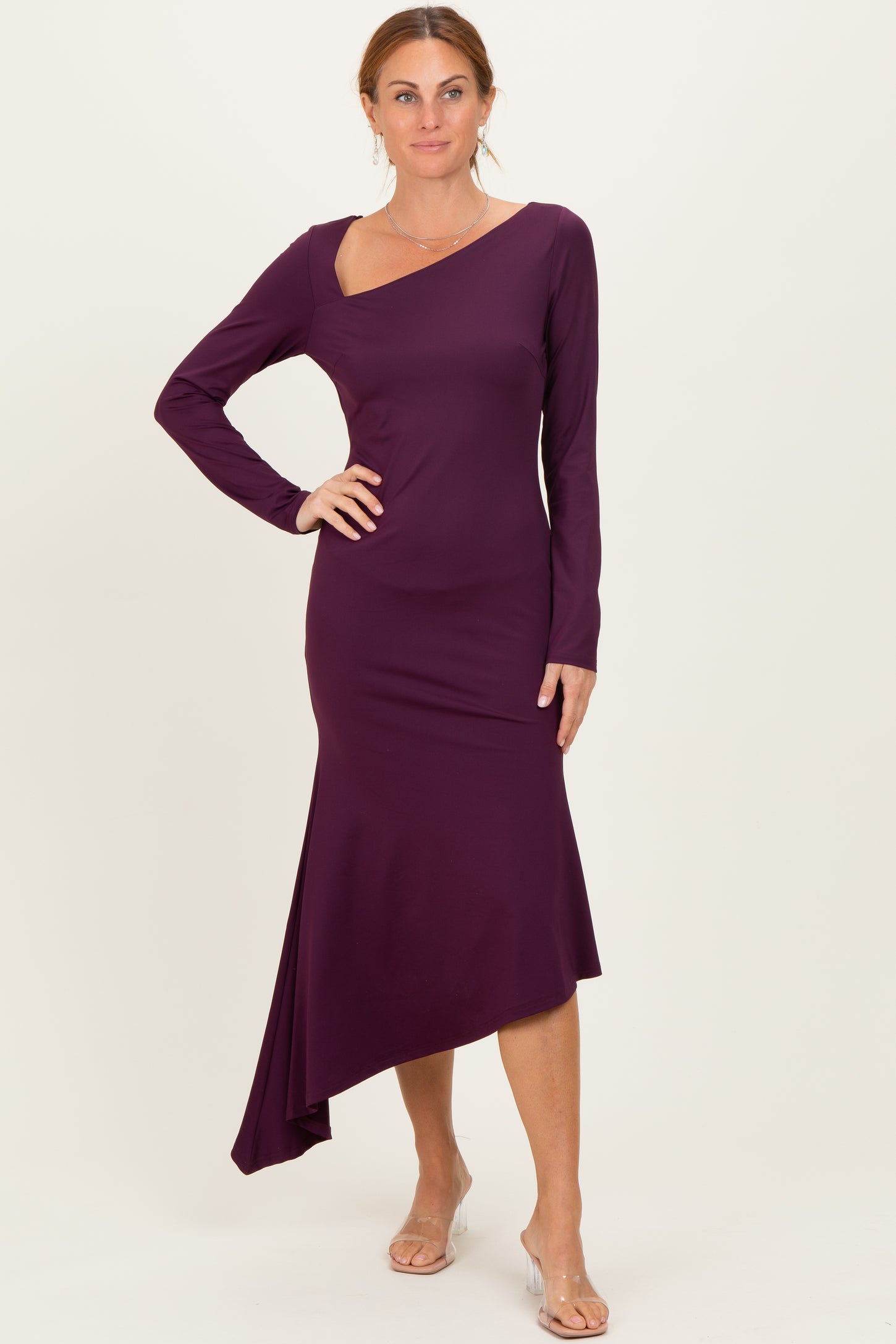 woman wearing a long sleeve burgundy asymmetrical dress with a diagonal hem and a scoop neckline