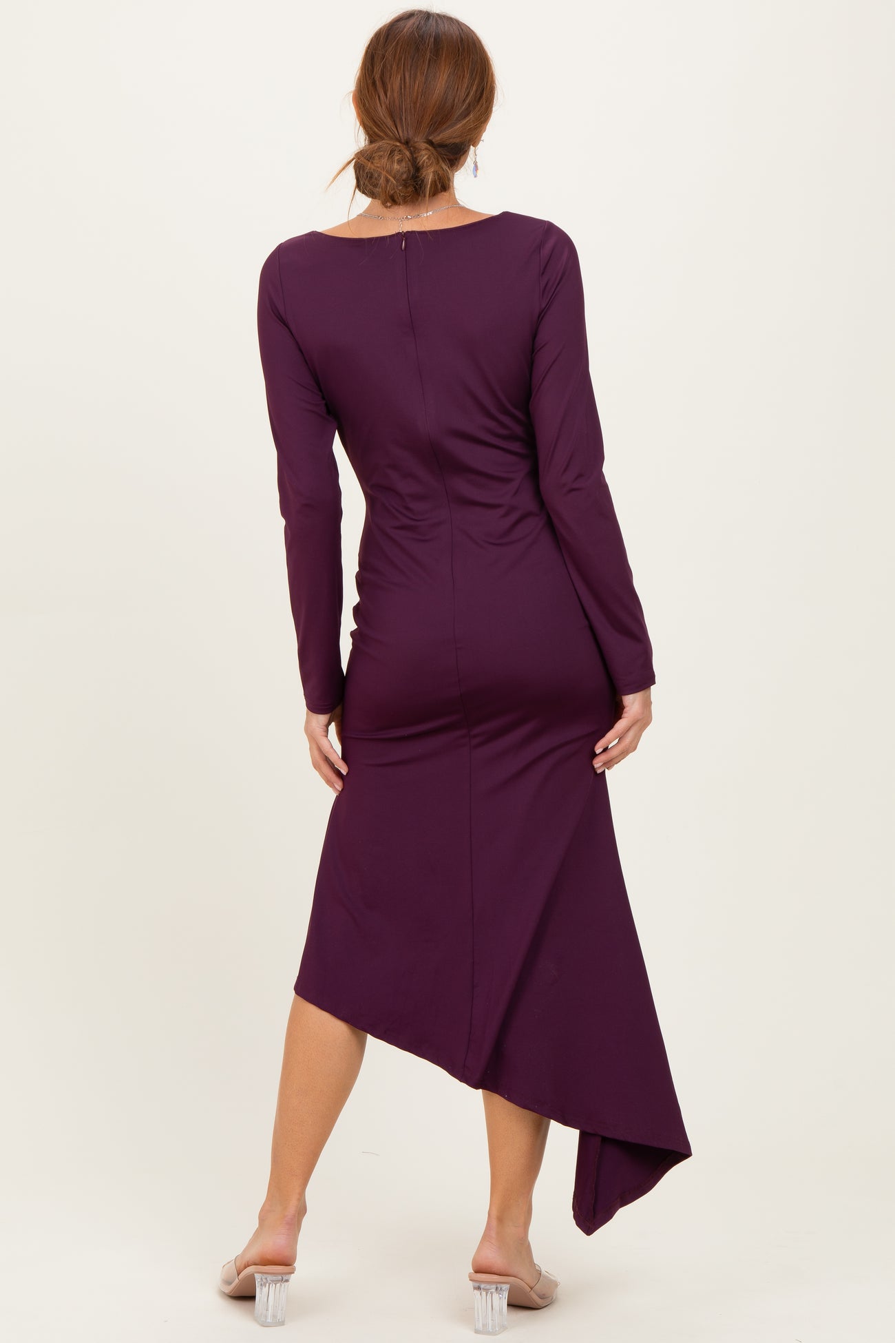 woman wearing a purple long sleeve dress with an asymmetrical hemline, seen from the back