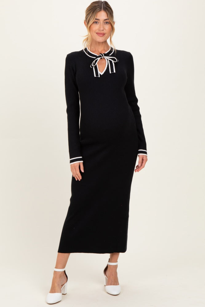 woman wearing a black ribbed maternity dress with a tie neckline and white stripe details, showcasing her baby bump