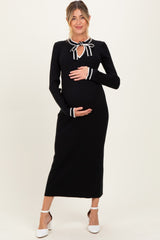 woman wearing a black maternity dress with a tie neck detail, holding her baby bump
